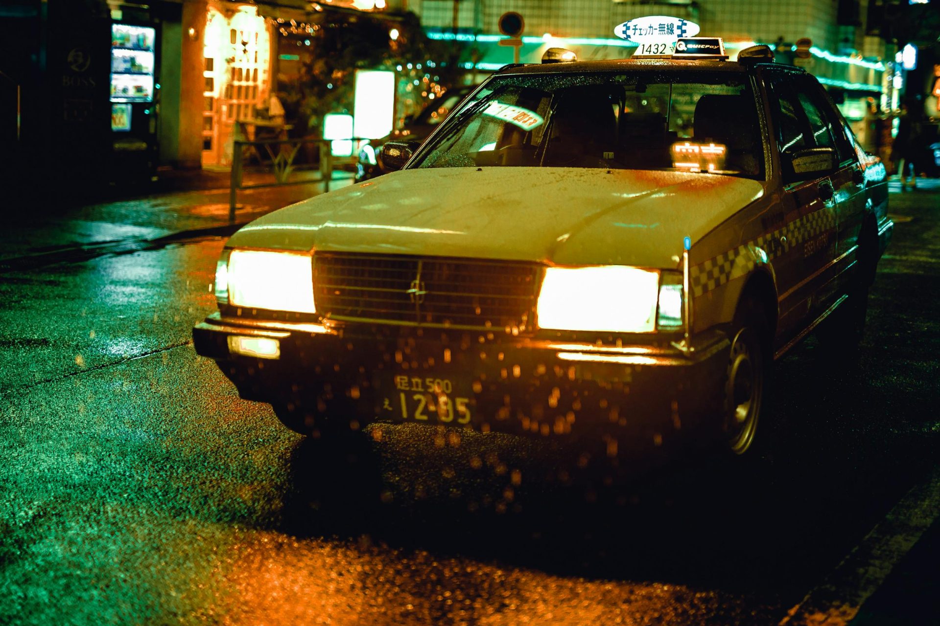 Ein gelbes Taxi fährt nachts durch regnerische Straßen in Tokio, Japan.